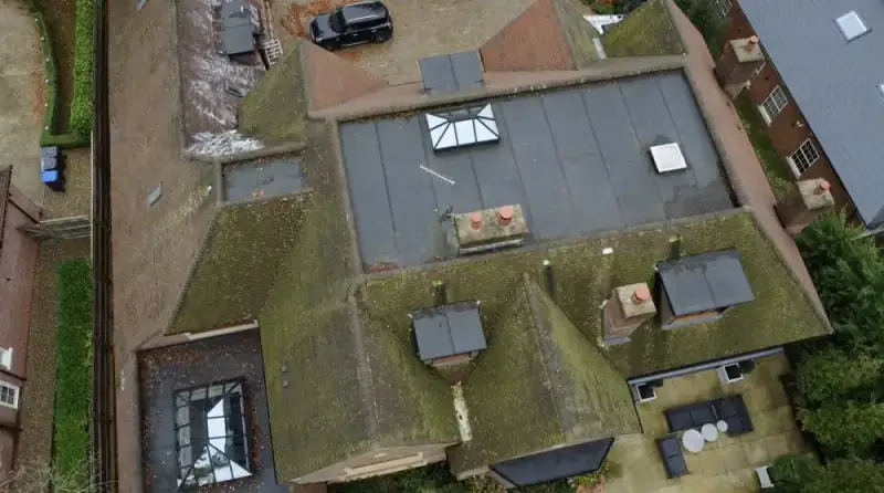Moss and debris built up on a tiled roof before specialist roof scraping