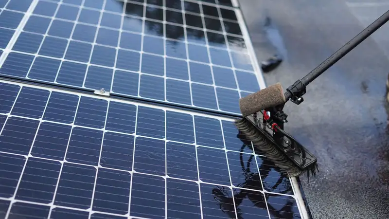 Solar panels being cleaned with a soft brush on a pole